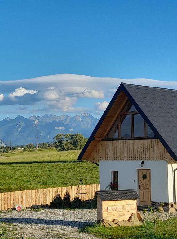 a white building with a wooden roof and mountains in the background at Kotelnica View in Groń