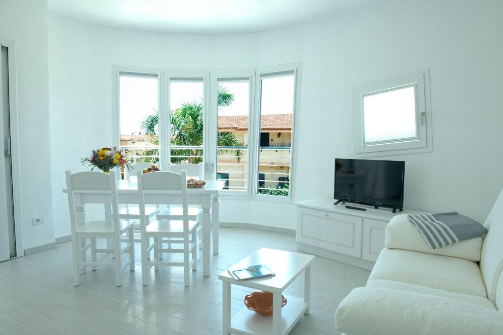 a white living room with a table and a couch at La Casa di Gianluca in Golfo Aranci