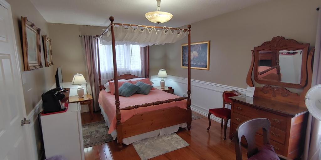 a bedroom with a canopy bed with a mirror and a dresser at BobcaygeonB&B in Kawartha Lakes