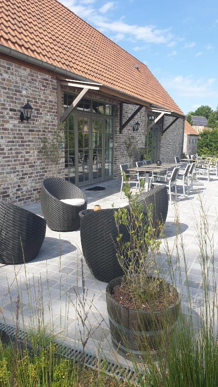 a patio with chairs and tables in front of a building at B&B 't Meesterhof in Deinze