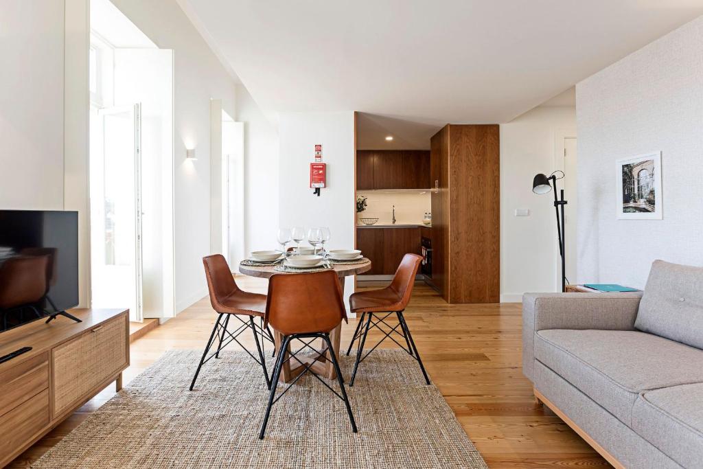 uma sala de estar com uma mesa e cadeiras e um sofá em Stunning Duplex Near River by LovelyStay no Porto
