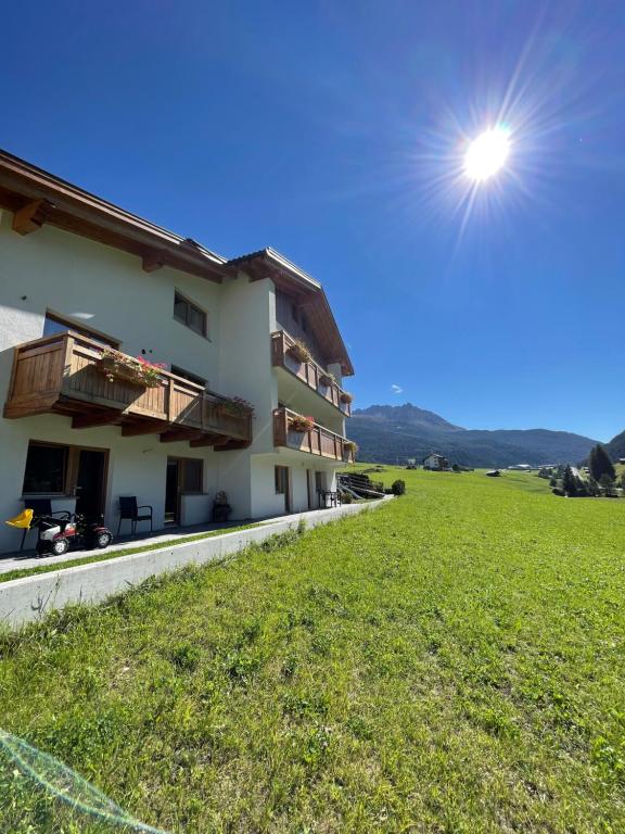 a building with a green field in front of it at Alpenrose-Apart in Nauders
