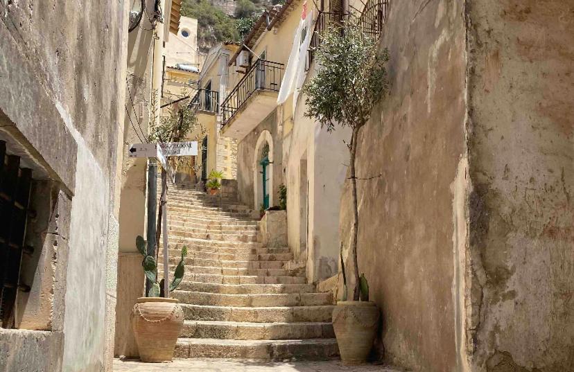 an alley with stairs and potted plants in a town at Intown - Dammuso in pieno centro storico in Scicli