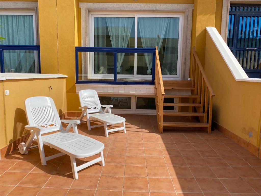 a porch with two white chairs and a staircase at Family Heaven - No Stress Holidays in El Cotillo