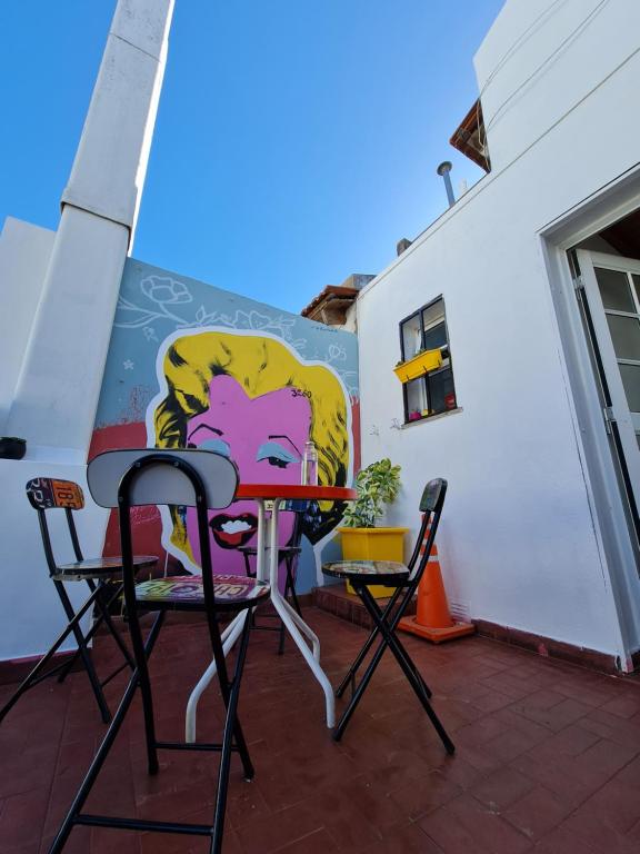uma mesa e cadeiras num pátio com uma pintura na parede em 3260HOSTEL em Concepción del Uruguay