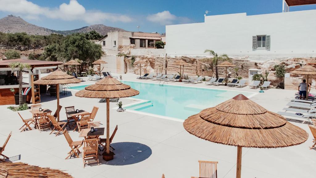 a resort with a pool with chairs and umbrellas at L'Oasi Villaggio Albergo in Favignana
