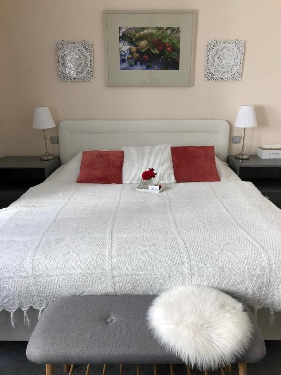 a bedroom with a white bed with two red pillows at Pension a restaurace Filip II in Mariánské Lázně