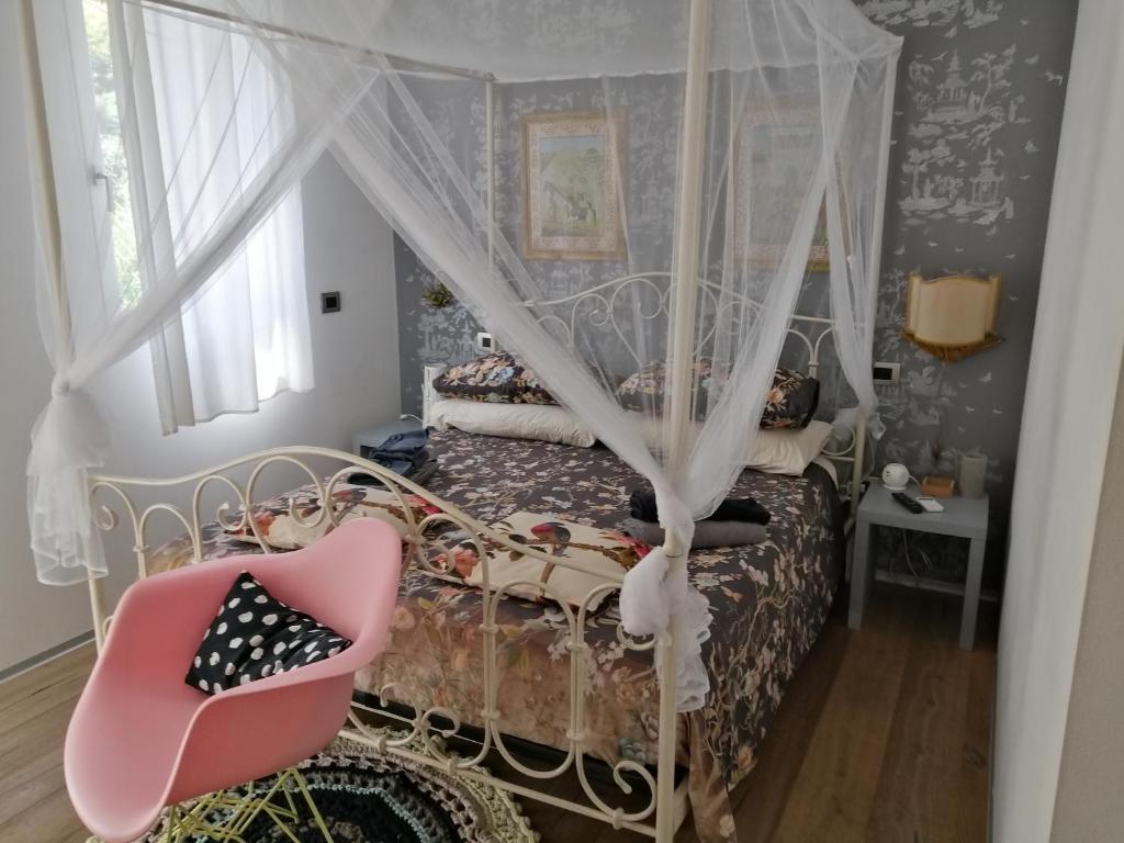 ミラーノにあるVia Dei Dori B&Bのベッドルーム(ピンクの椅子と天蓋付きベッド付)