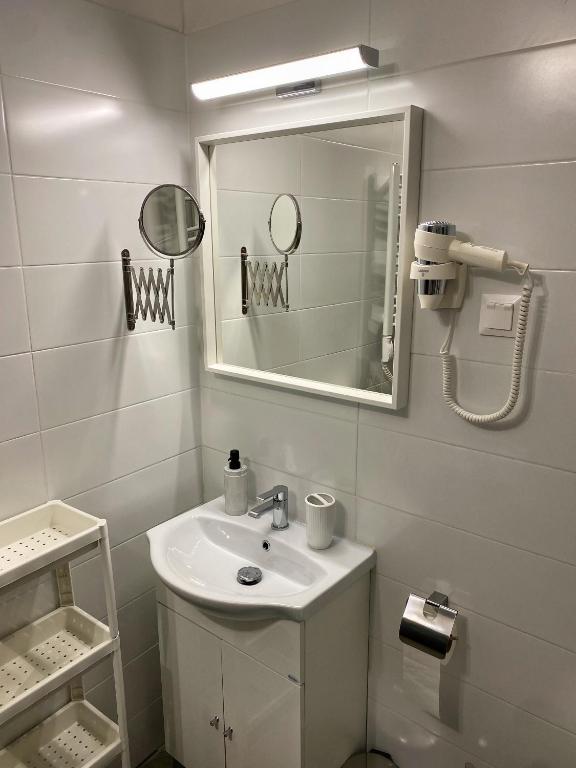 ein weißes Badezimmer mit einem Waschbecken und einem Spiegel in der Unterkunft Málna Apartman Juventus in Balatonföldvár