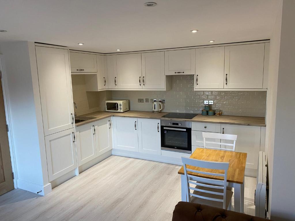 High Heaton的住宿－Newly Refurbished Entire Apartment - South Gosforth, Newcastle，厨房配有白色橱柜和桌椅