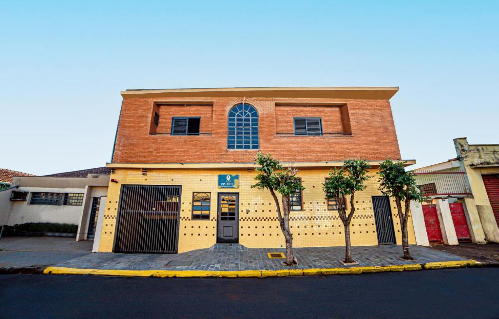 a yellow building with trees in front of it at RP HOTEL in Ribeirão Preto