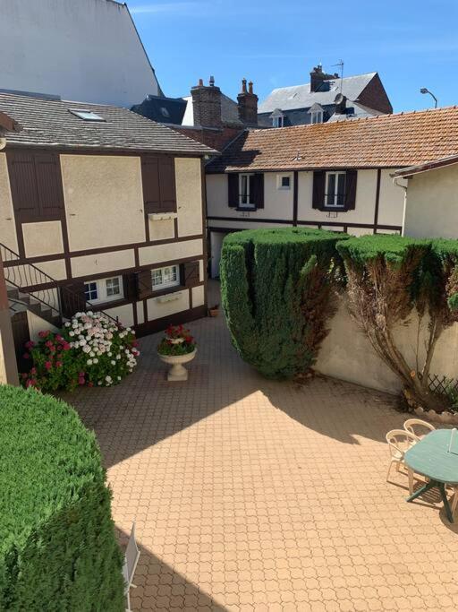 - une cour avec deux maisons, une table et des chaises dans l'établissement Résidence de l’Hippodrome, à Deauville