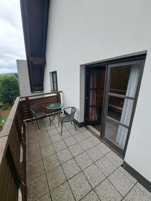 a patio with a table and chairs on a balcony at U Bernardýna in Harrachov