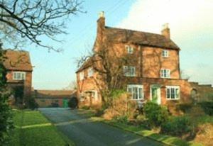 ein großes Backsteinhaus mit einer Straße davor in der Unterkunft Ingon Bank Farm Bed And Breakfast in Stratford-upon-Avon