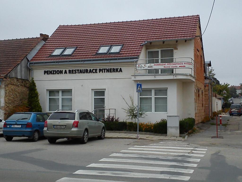 a building with two cars parked in front of it at Penzion Pitnerka in Hustopeče