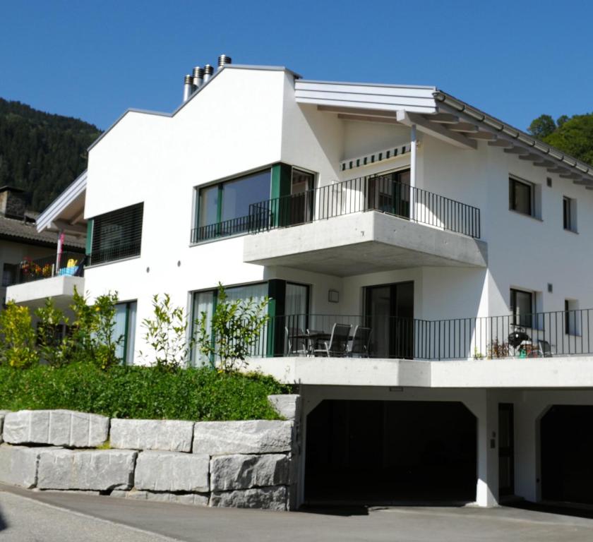 ein weißes Haus mit einem Balkon und einer Auffahrt in der Unterkunft Wohnen wie Zuhause in Sagogn