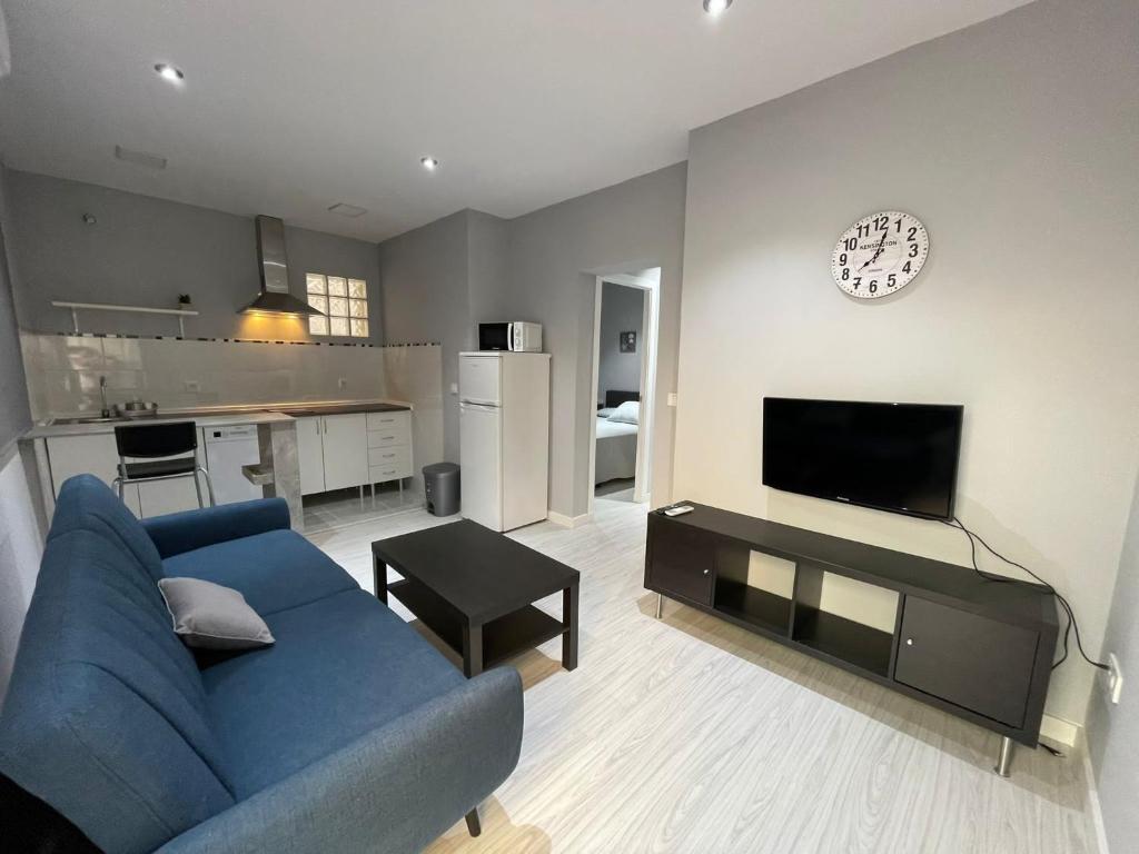 a living room with a blue couch and a clock on a wall at Villas Adrian in Jerez de la Frontera