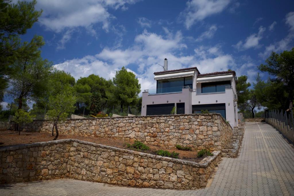 a stone wall in front of a white house at Pines sea view villa 170 sqm in Theologos in Theologos