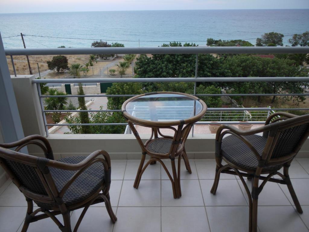 a balcony with two chairs and a table and a view of the ocean at Portela Apartments Kampoula in Keratokampos