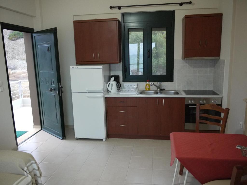 a kitchen with a white refrigerator and wooden cabinets at Portela Apartments Kampoula in Keratokampos