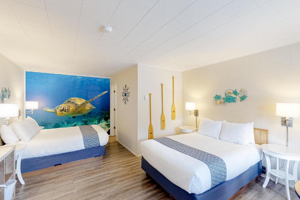 a hotel room with two beds and a fish painting at Lamplighter Inn II in Bandon