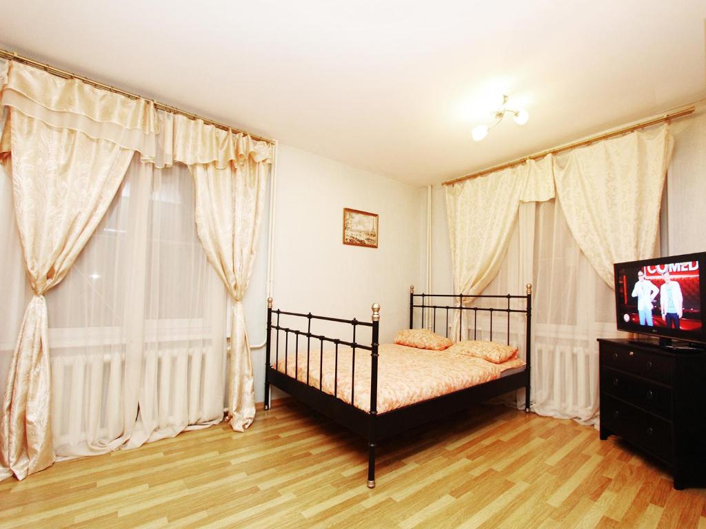 1 dormitorio con 1 cama, TV y cortinas en ApartLux Kuzminki, en Moscú