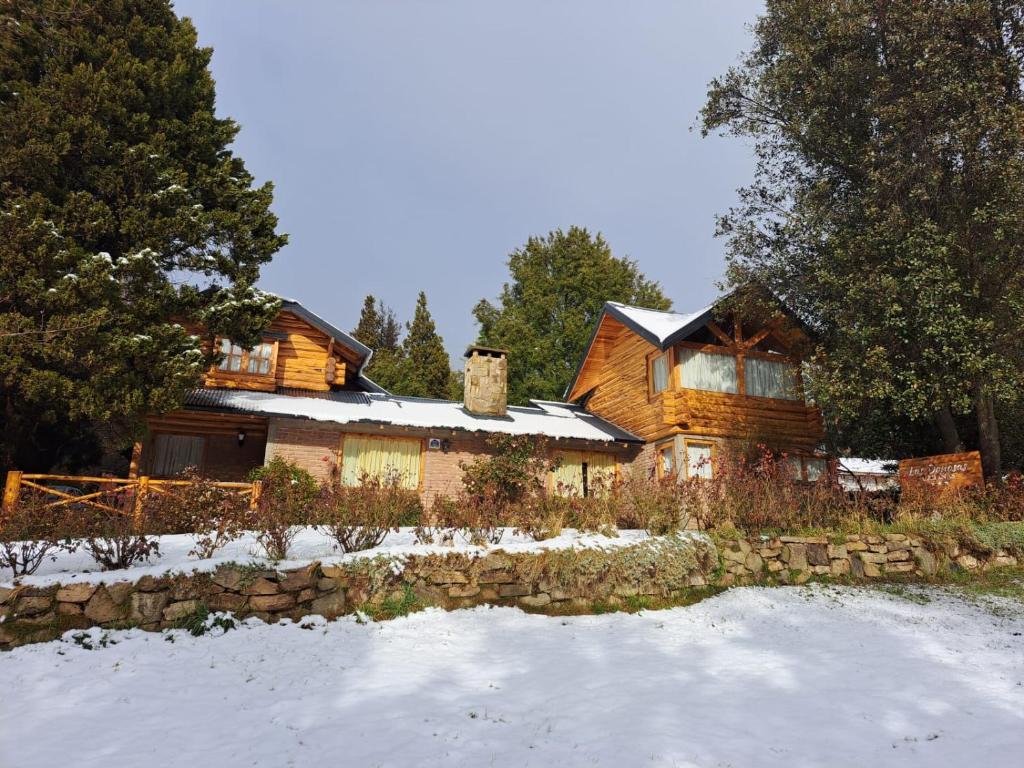 a log house in the snow with a stone wall at Cabañas Las Donosas in San Carlos de Bariloche