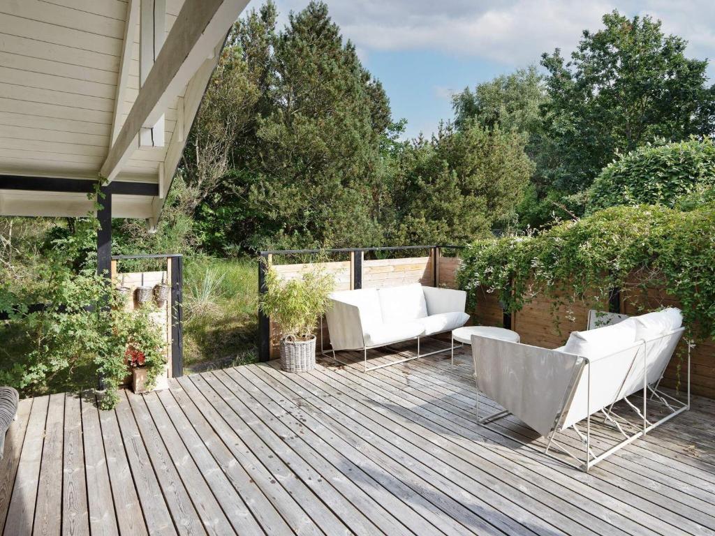 una terraza de madera con 2 sillas y un sofá. en Holiday home Vejby XXXVI en Vejby