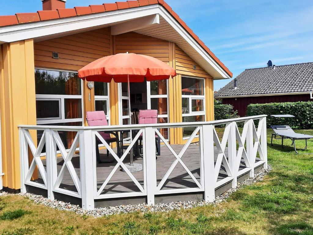 グレーミッツにあるThree-Bedroom Holiday home in Grömitz 18のデッキ(椅子2脚、パラソル付)が備わる家