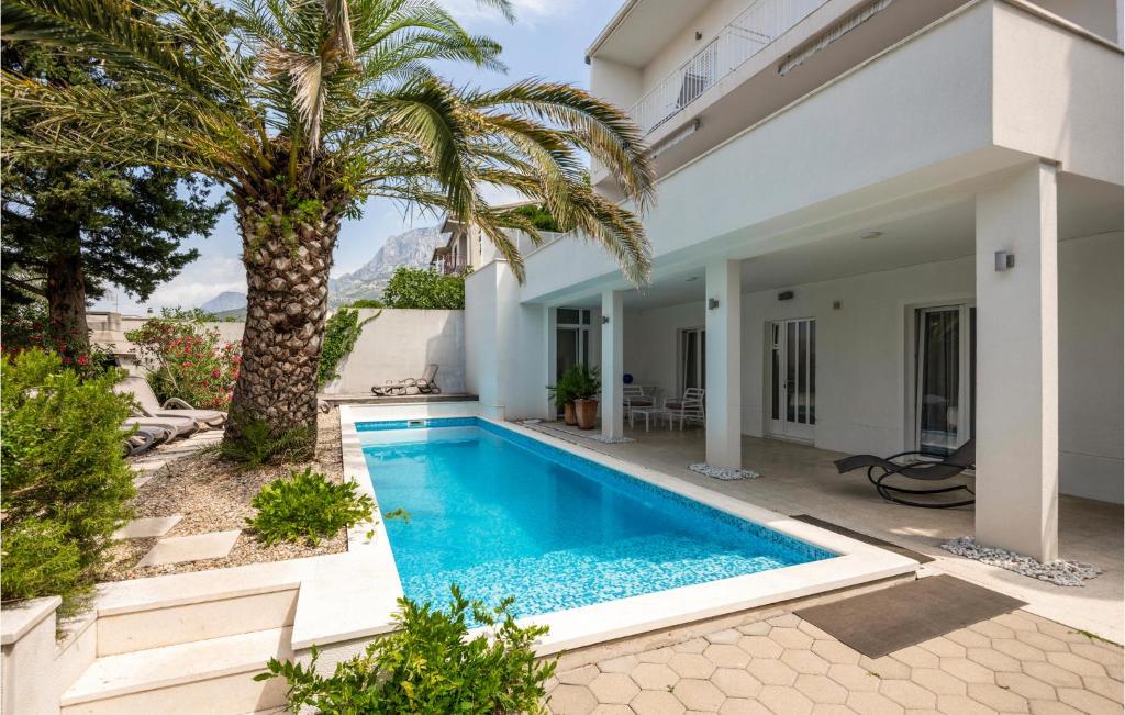 a swimming pool in the backyard of a house with a palm tree at Stunning Apartment In Makarska With 3 Bedrooms, Wifi And Heated Swimming Pool in Makarska