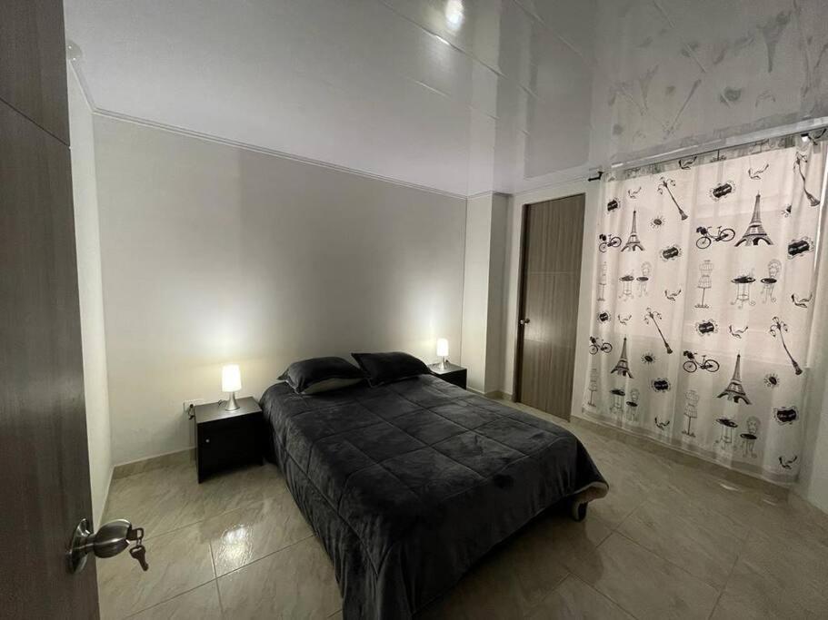 a bedroom with a bed and two lamps and a curtain at Hermoso apartamento completo 2 habitaciones - ubicación excelente para transporte al parque del café y PANACA in Armenia