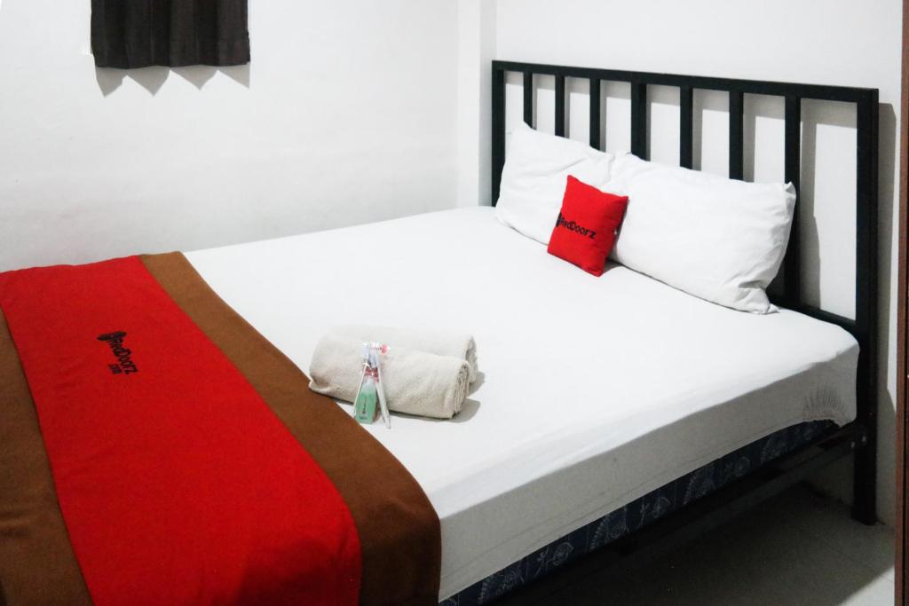 a bedroom with a white bed with red and white pillows at RedDoorz at Jalan Somba Opu Losari in Makassar