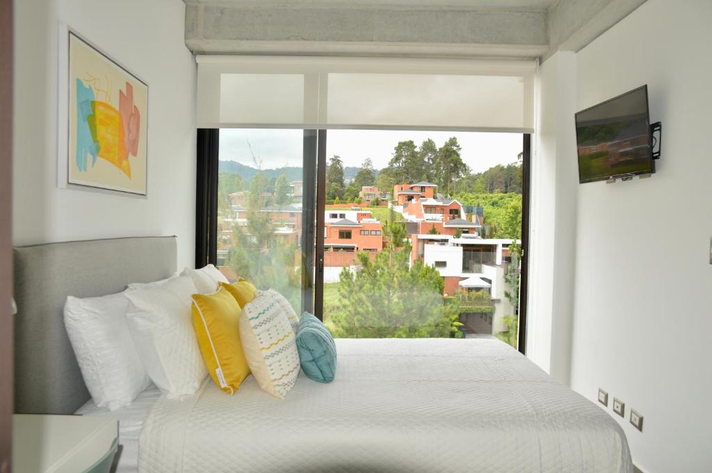 a bedroom with a bed and a large window at Cozy Stays Cayala Apartments (407) in Guatemala