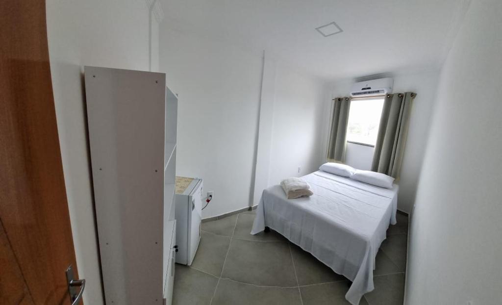een kleine slaapkamer met een bed en een raam bij Kitnet Super in Cumuruxatiba
