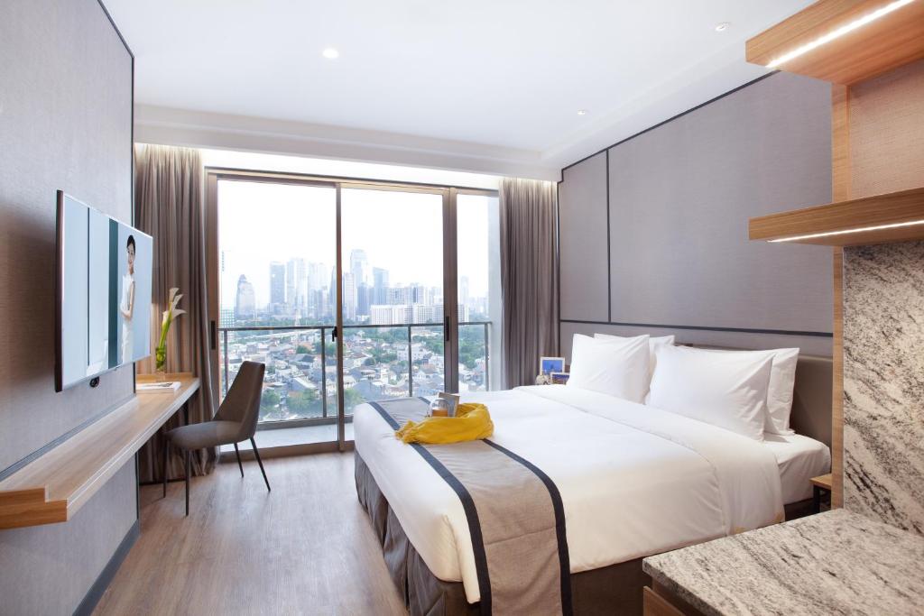ein Hotelzimmer mit einem Bett und einem großen Fenster in der Unterkunft Somerset Sudirman Jakarta in Jakarta
