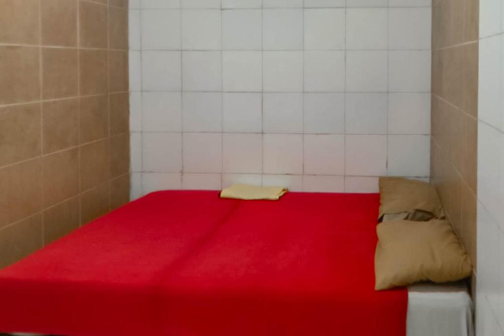 een rood bed in een kamer met witte tegels bij Hotel Arimbi 3 RedPartner in Bandung