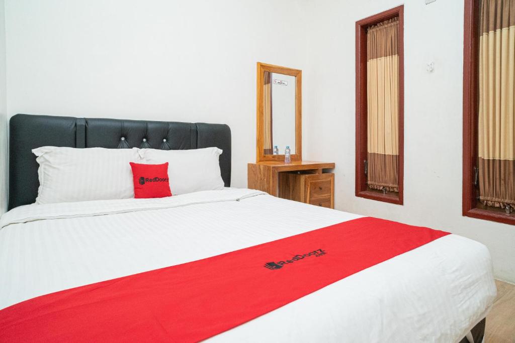 una camera da letto con una coperta rossa su un letto di RedDoorz Syariah At Sulfat Malang a Malang