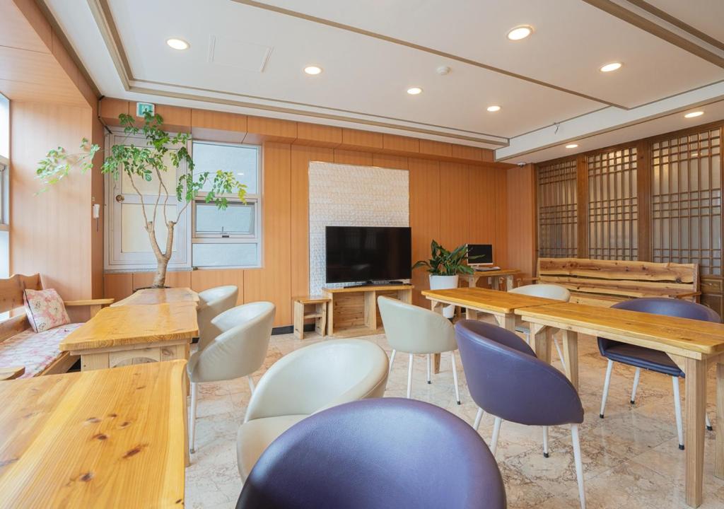Habitación con mesas, sillas y TV. en J2 Family Hotel, en Jeju