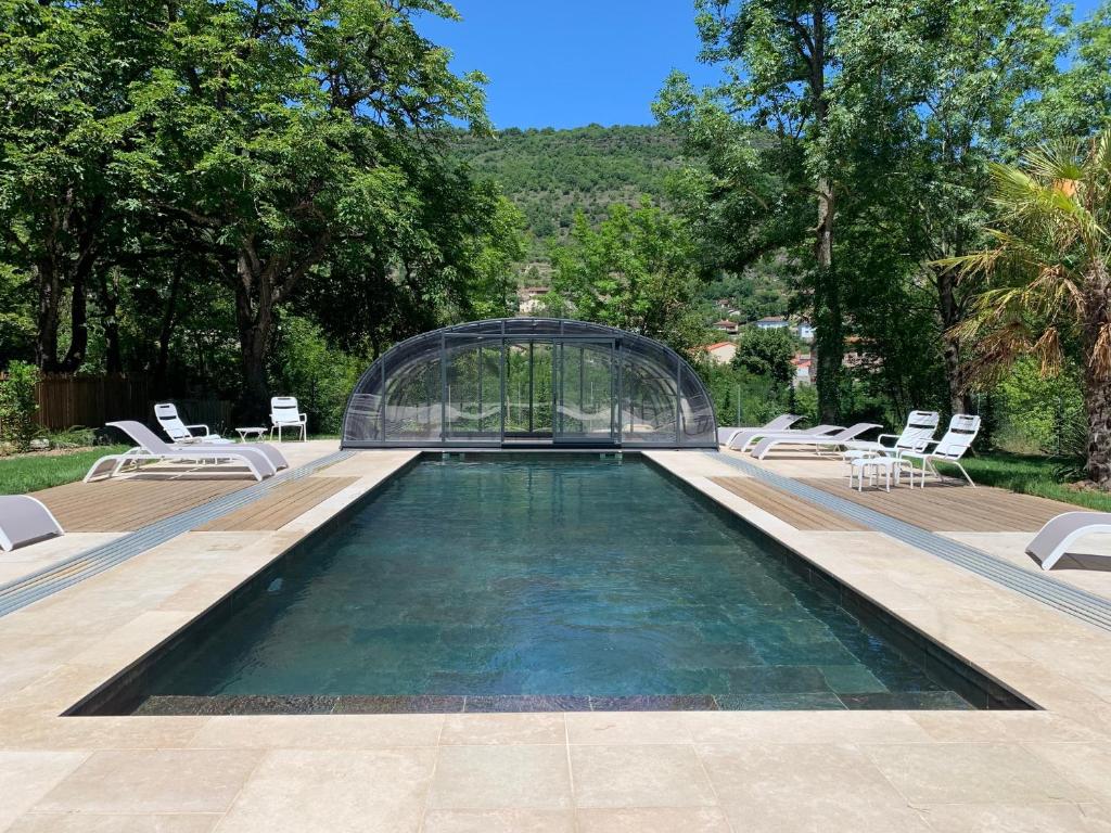 einen Pool mit einem Glashaus und Stühlen in der Unterkunft Domaine le Vaxergues in Saint-Affrique