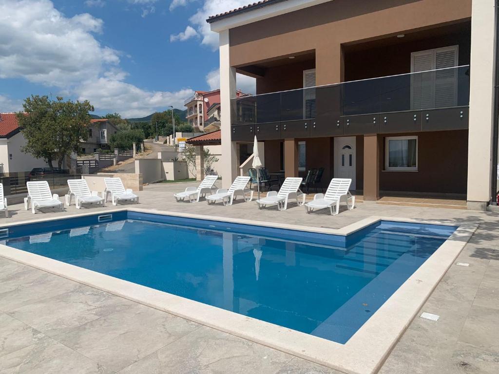 a swimming pool with lounge chairs and a house at Apartment Ankica in Crikvenica
