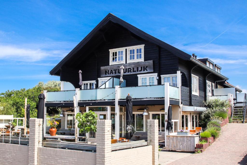 ein Gebäude mit einem Schild, das in Kürze in der Unterkunft Appartementen Natuurlijk in Egmond aan Zee