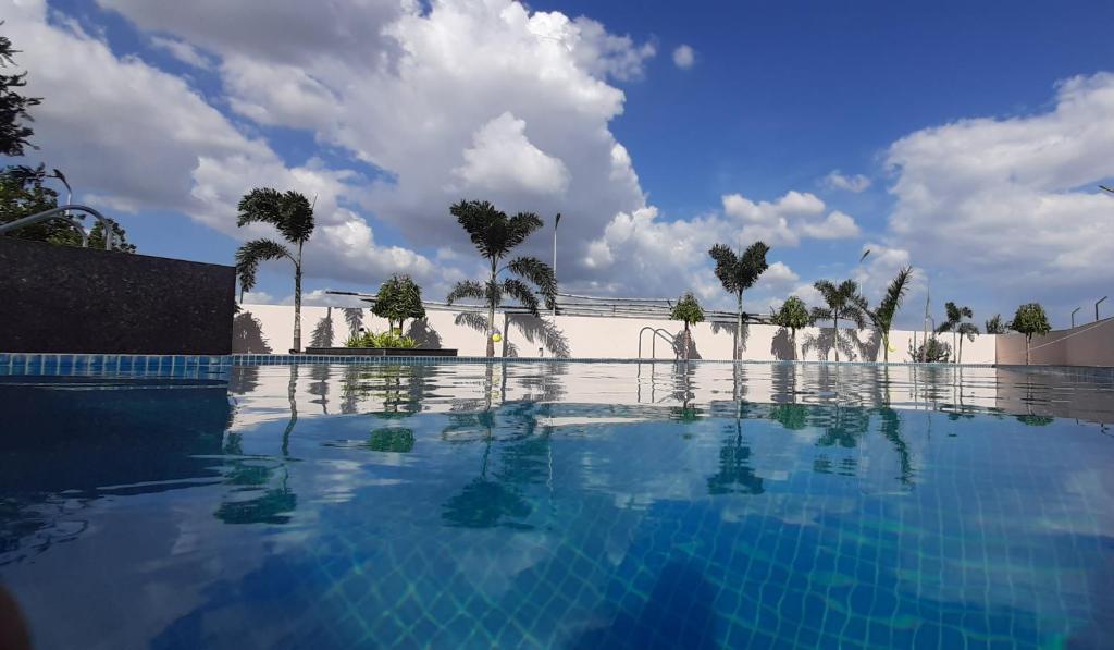 uma grande piscina com palmeiras ao fundo em ECONEST HOTEL em Tarapith