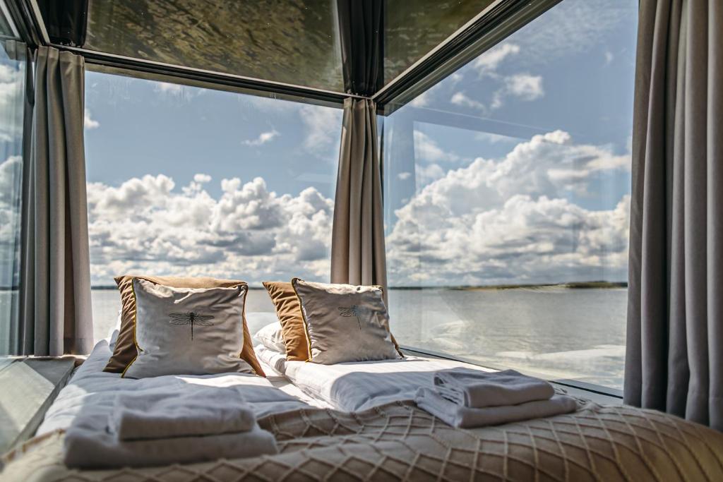 a bed in a room with a large window at Domki na wodzie - HT Houseboats - with sauna, jacuzzi massage chair in Mielno