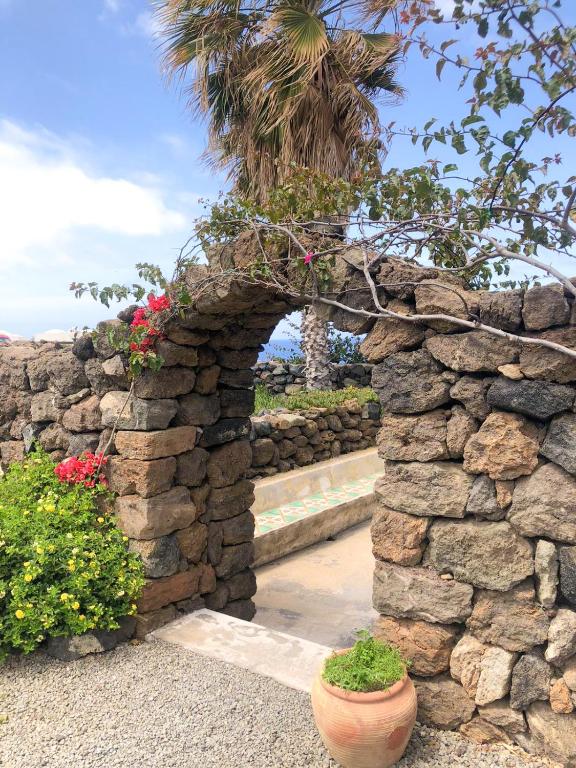 a stone wall with a stone arch with flowers at Dammuso Cinzia, incantevole fronte mare in Pantelleria