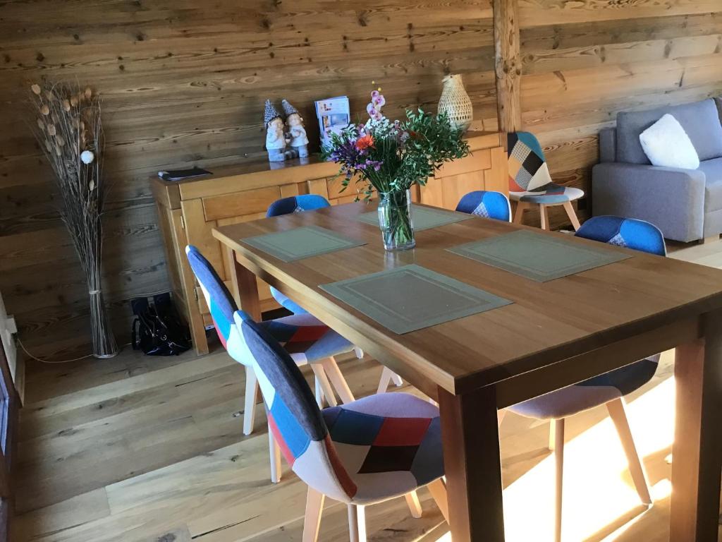 a wooden table with chairs and a vase of flowers on it at Duplex Bellevue in Gérardmer