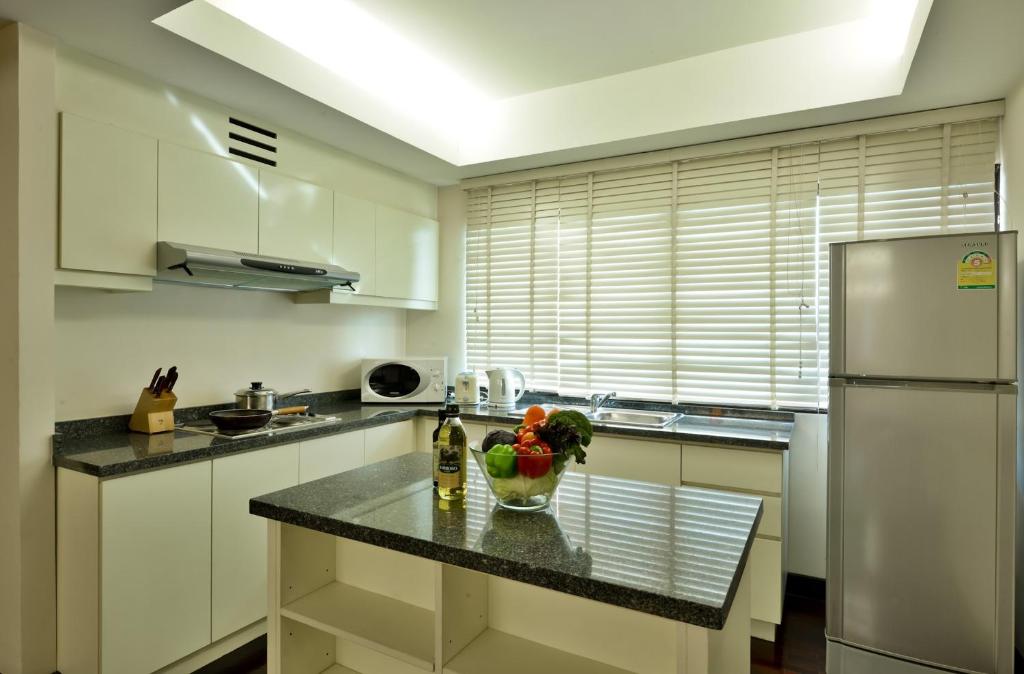 A bright kitchen includes a central granite island, cooktop, sink, microwave and full-height refrigerator.