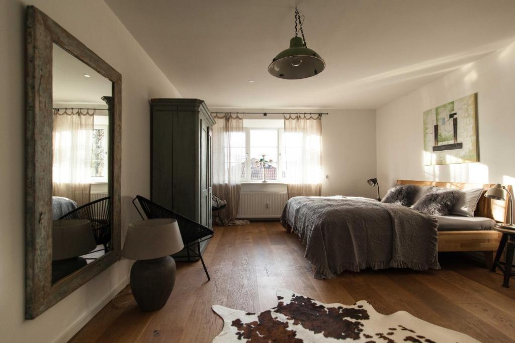 um quarto com uma cama, um espelho e um sofá em Modern-bayrisches Apartment mit Seeblick em Tegernsee