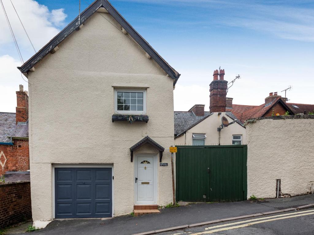 a white brick house with a green garage at Dove Cottage in Ruthin