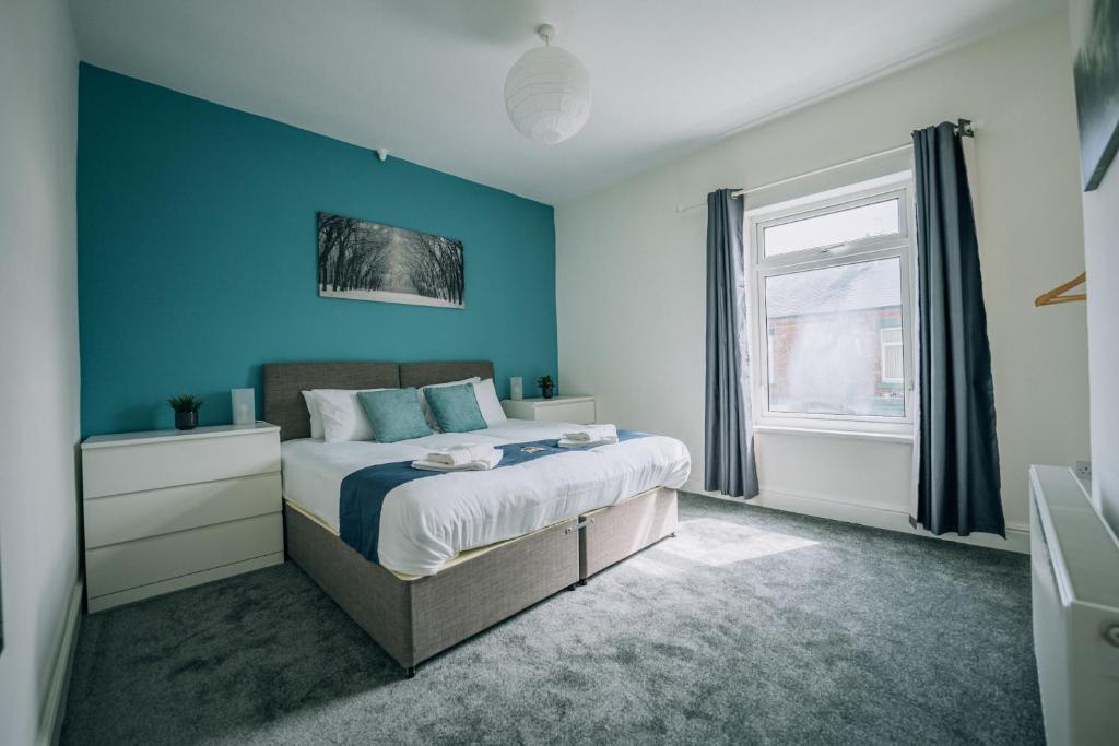 a bedroom with a bed with blue walls and a window at Barron House By Horizon Stays in Darlington