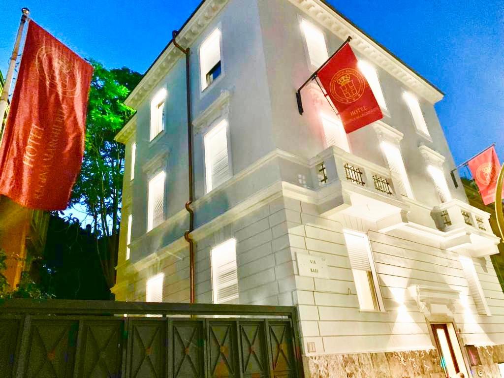 un bâtiment blanc avec deux drapeaux rouges sur lui dans l'établissement Hotel Regina Margherita, à Rome